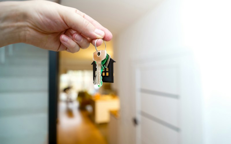 Hand holding a set of house keys at an open front door