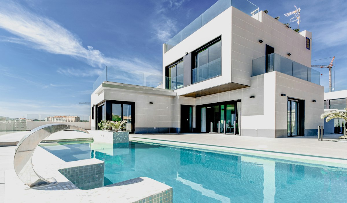 Modern white two-storey home with large windows under a blue sky